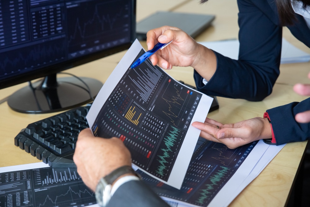 brokers-discussing-trading-strategy-holding-papers-with-financial-data-pointing-pen-charts-cropped-shot-broker-job-stock-market-exchange-concept