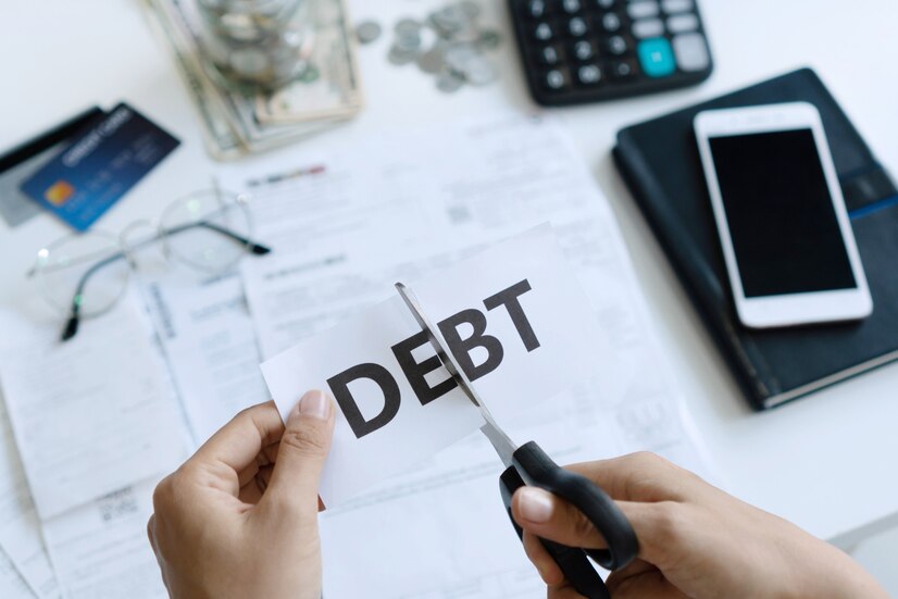 top-view-woman-hands-cutting-paper-with-word-debt-written-it